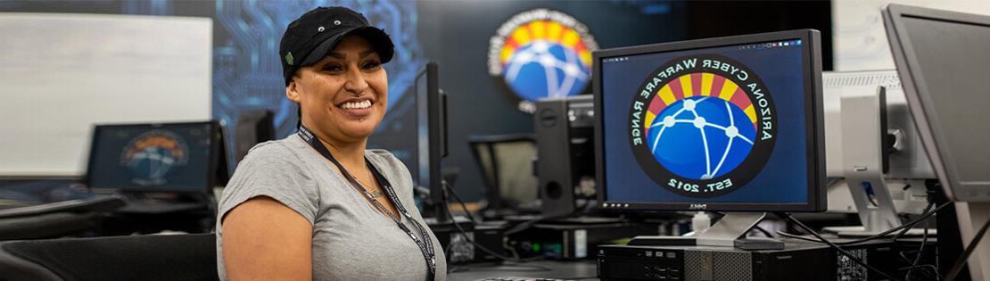 在皮马的网络战靶场课上，一名学生微笑着坐在电脑前