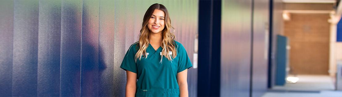 皮马大学西校区，一名护理专业的学生站在墙边微笑