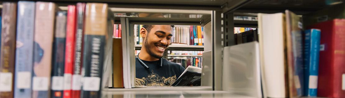 在皮马大学图书馆，一名学生微笑着看一本书